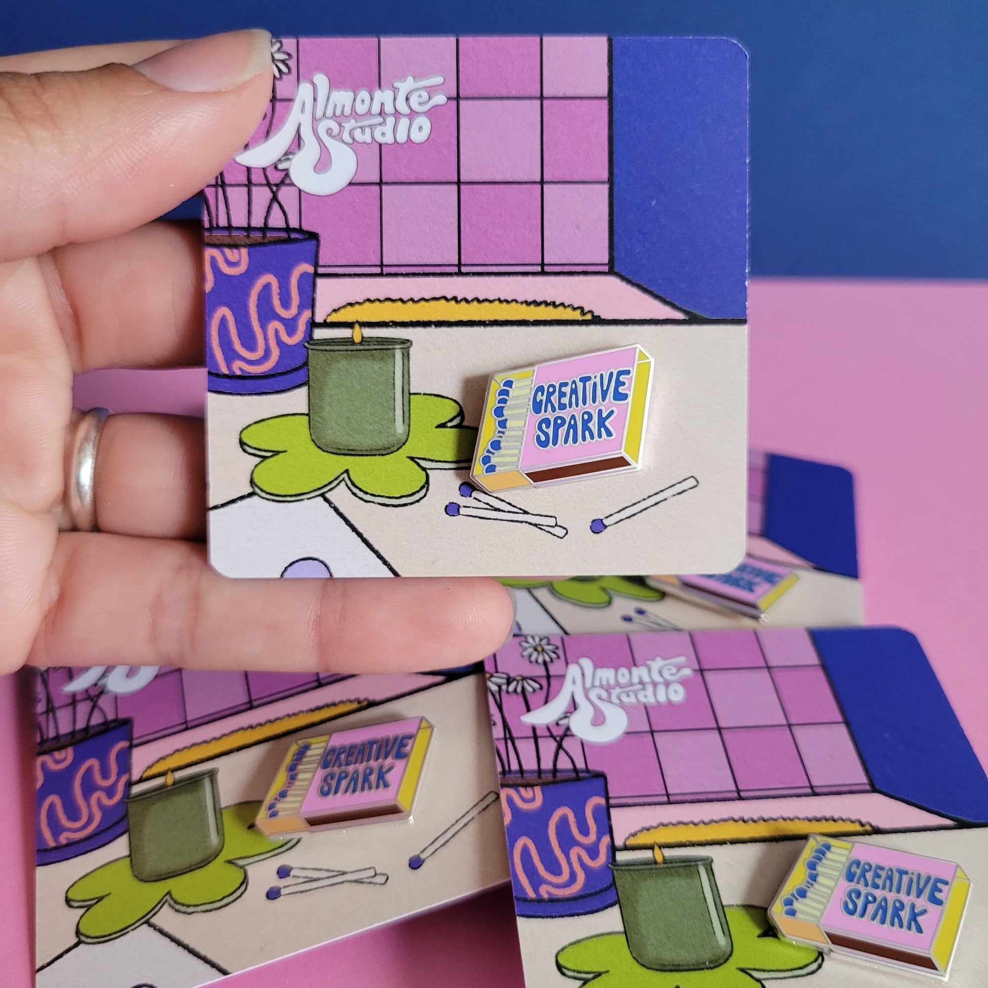 Colorful geometric blocks with 'Creative Spark' pin held by a hand on a pink and blue background.