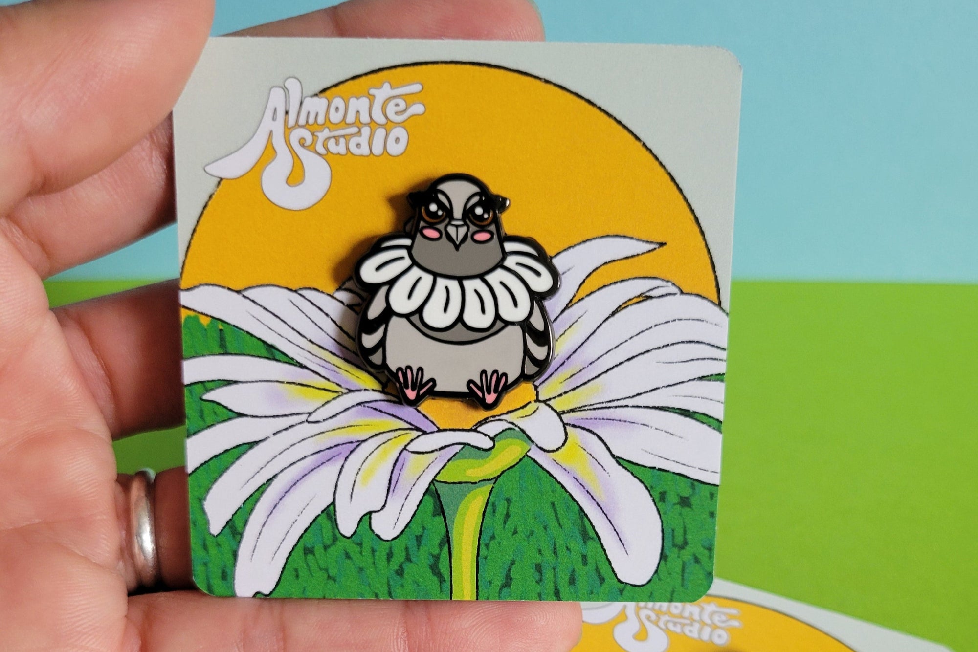 Three cards with a pigeon wearing a daisy  held by a hand against a colorful background