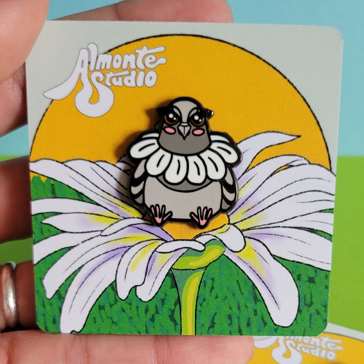 Three cards with a pigeon wearing a daisy  held by a hand against a colorful background