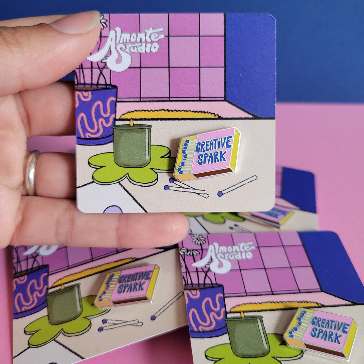 Colorful geometric blocks with 'Creative Spark' pin held by a hand on a pink and blue background.