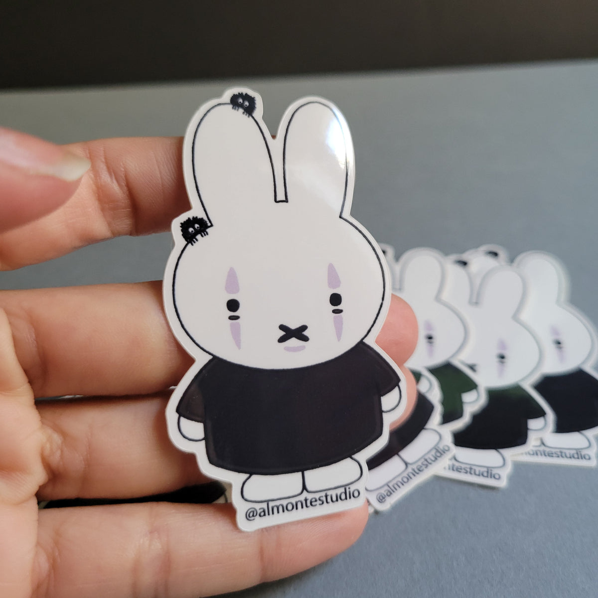 Hand holding a set of cartoon-style stickers with a neutral background
