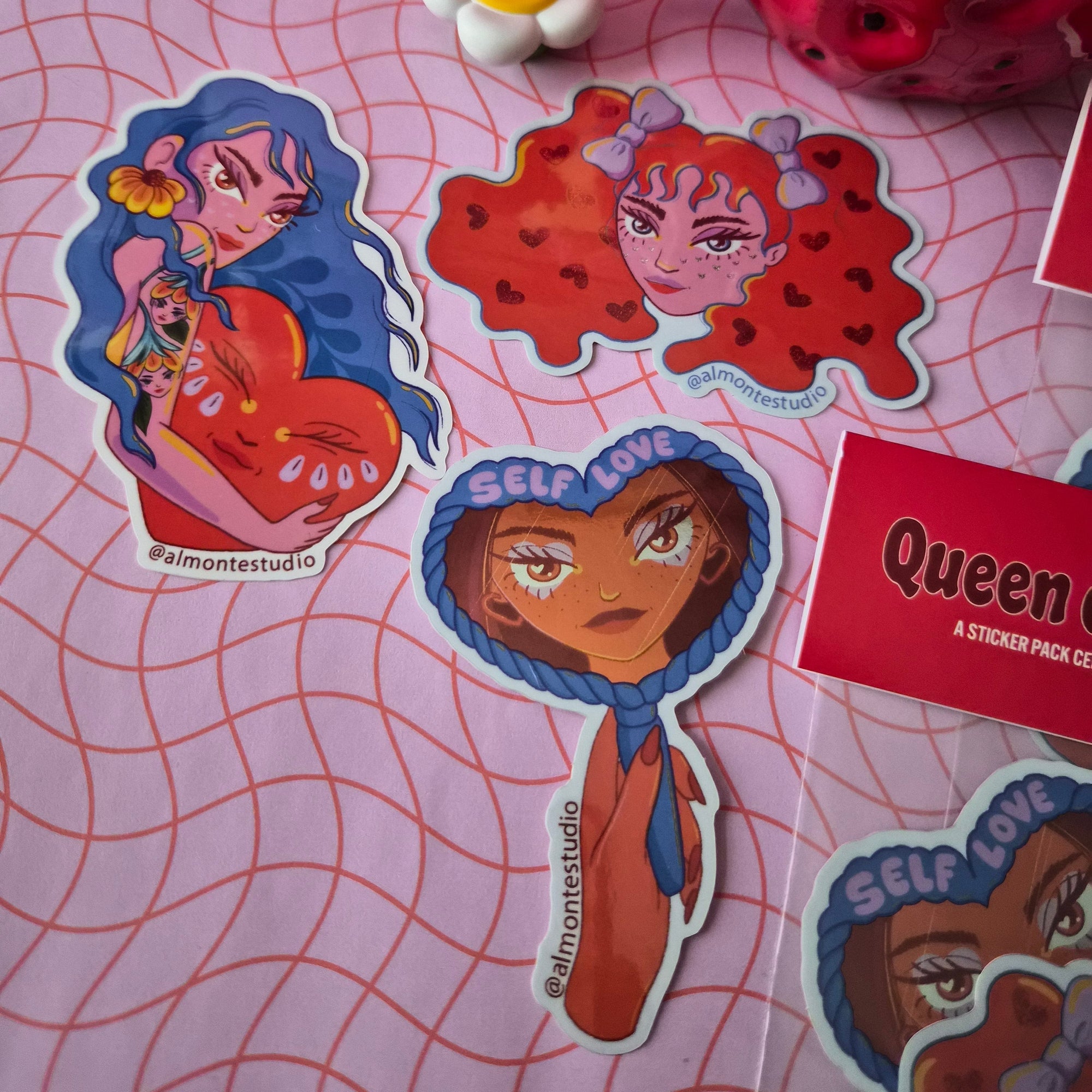 Stickers with artistic designs on a pink surface with grid pattern